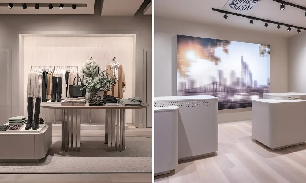 Modernes Modegeschäft in neutralen Farben: links ein stilvoll arrangierter Verkaufsbereich mit Kleidung und Accessoires, rechts ein eleganter Kassenbereich mit großem, unscharfem Stadtbild an der Wand.