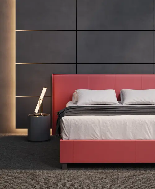 Modernes Schlafzimmer mit einem roten Polsterbett, dunkler Wandverkleidung, stimmungsvoller Beleuchtung und einem Beistelltisch mit Designerlampe.