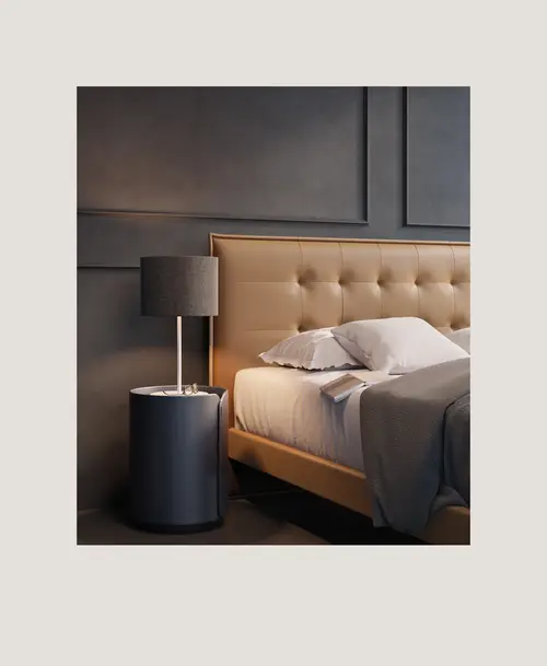 Elegantes Schlafzimmer mit gepolstertem Bett in warmen Beige-Tönen, grauem Nachttisch und passender Lampe vor dunkler Wandverkleidung.
