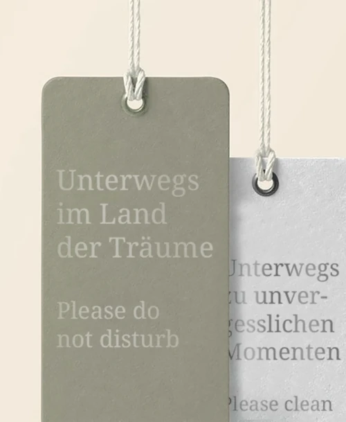 Türanhänger in natürlichen Farben mit den Texten 'Unterwegs im Land der Träume – Please do not disturb' und 'Unterwegs zu unvergesslichen Momenten – Please clean'.