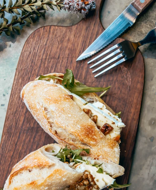 Frisch belegtes Baguette mit Rucola, Walnüssen und Käse auf Holzbrett – rustikale, saisonale Café-Küche im HORST Berg Café, serviert mit Liebe zum Detail.