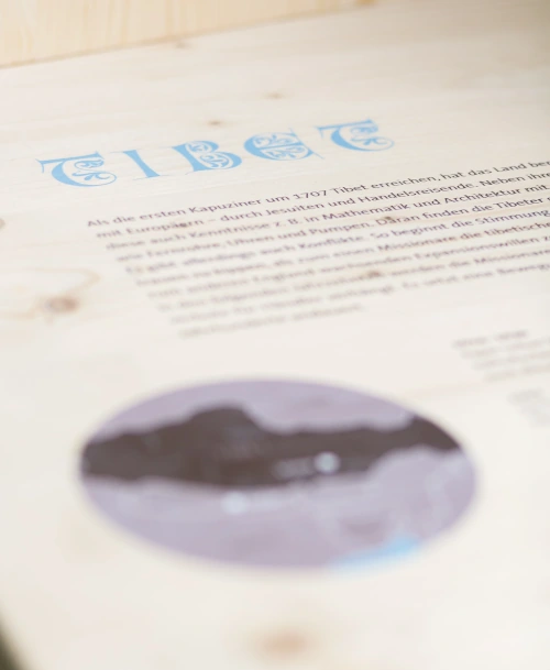 Detailansicht einer Informationstafel in der Ausstellung mit dem Wort „TIBET“ in verziertem blauen Schriftzug und einem Text über die Kapuzinermissionen in der Region.