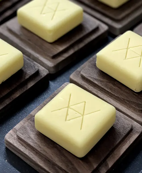 Handgefertigte Butterwürfel mit eingraviertem Logo, präsentiert auf dunklen Holzuntersetzern