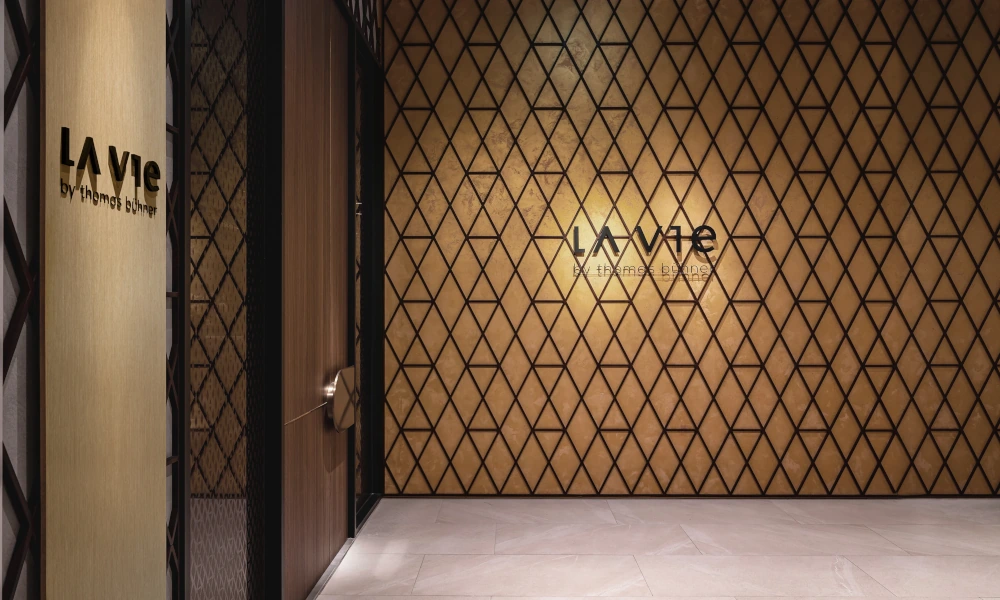 Eingangsbereich des Restaurants 'La Vie by Thomas Bühner' in Taipeh mit goldener Wand und rautenförmigem Muster.