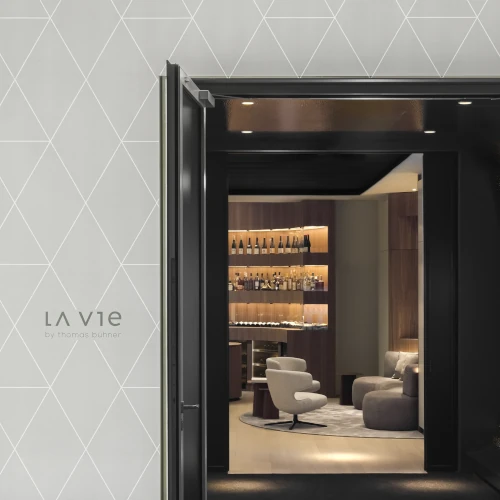 Offener Eingang zum LA VIE by Thomas Bühner in Düsseldorf mit Blick auf elegante Lounge, Weinschrank und Designer-Sessel.