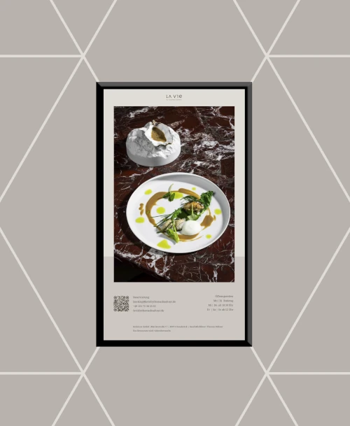 Feines Dessert im LA VIE by Thomas Bühner, kunstvoll angerichtet auf weißem Teller und dunkler Marmorplatte als Untergrund.