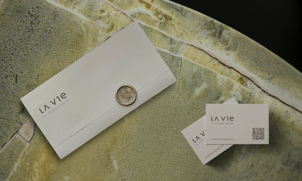 Zwei hochwertige Geschenktaschen mit Logo von LA VIE by Thomas Bühner auf Holztisch – elegantes Design in Rosa mit weißer Kordel.