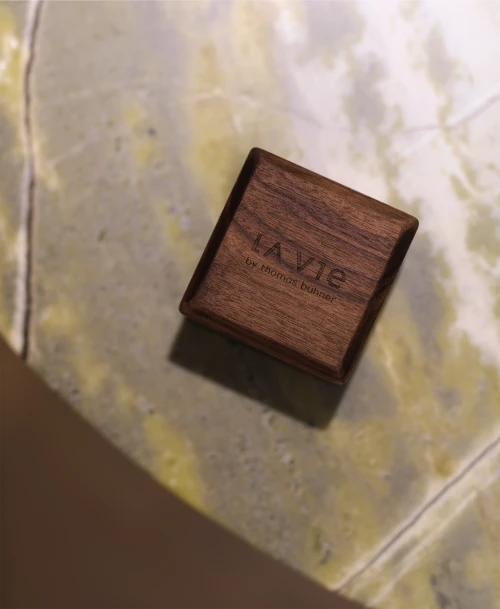 Kleine Holzbox mit Logo von LA VIE by Thomas Bühner auf grünem Natursteintisch – hochwertiges Detail mit Branding-Gravur.