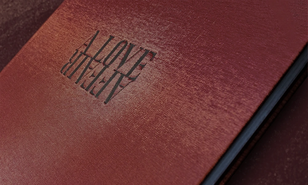 Nahaufnahme eines roten Hardcover-Buches mit geprägtem Titel "A LOVE SUPREME" auf dem Einband.