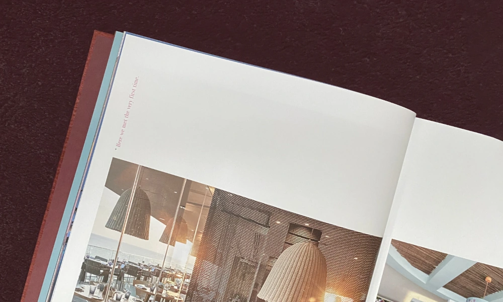 Aufgeschlagenes Buch mit Architektur- und Innenraumfotografien, liegend auf einer dunklen Oberfläche.