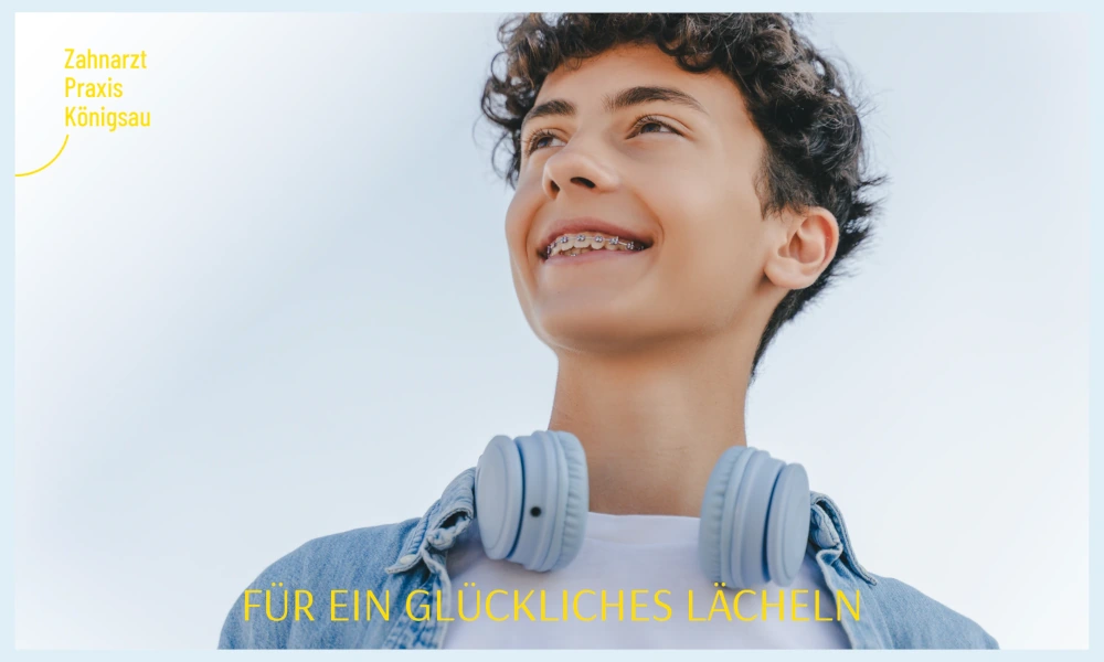 Jugendlicher mit Zahnspange und Kopfhörern, lächelnd vor blauem Himmel, mit dem Text 'Für ein glückliches Lächeln' und Logo der Zahnarztpraxis Königsaus