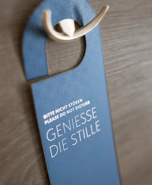 Stilvolles „Bitte nicht stören“-Schild des „Hotel Stadt Kassel“ in Blau mit der Aufschrift „Genieße die Stille“, aufgehängt an einer Holztür.