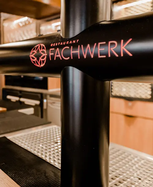 Schwarze Bierzapfanlage mit rotem Logo des Restaurants „Fachwerk“ im „Hotel Stadt Kassel“, stilvolles Theken-Design im Hintergrund.