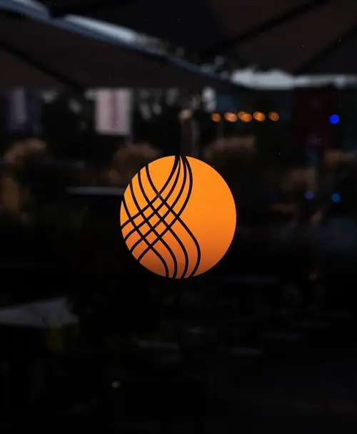 Leuchtendes orangefarbenes Logo von 'WACA' mit geschwungenem Linienmuster, vor einem dunklen Hintergrund.