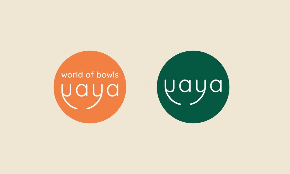 Logos des Gastro-Konzepts 'Yaya - World of Bowls' in Orange und Grün auf beigefarbenem Hintergrund.