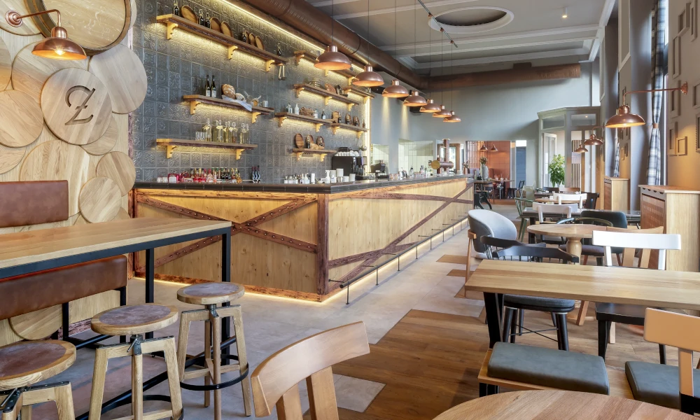 Innenraum des Zenz Wirtshauses mit heller Holzoptik, stilvoller Bar und modernen Sitzbereichen – einladendes Ambiente mit handwerklichem Charme und urbaner Gemütlichkeit.